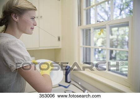 Woman washing crockery and looking through window View Large Photo Image Stock Photograph - Woman washing crockery and looking through window. Fotosearch