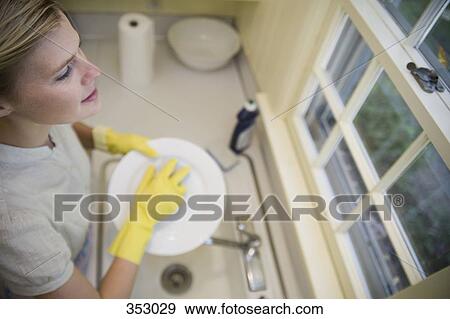 Woman washing up at kitchen sink and looking out of window View Large Photo Image Stock Photo - Woman washing up at kitchen sink and looking out of window. Fotosearch
