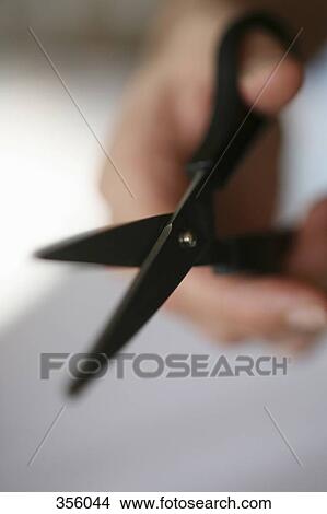 Defocused hand holding scissors View Large Photo Image Picture - Defocused hand holding scissors. Fotosearch