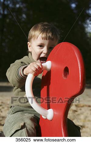 Young boy playing on spring ride in playground View Large Photo Image Stock Photography - Young boy playing on spring ride in playground. Fotosearch