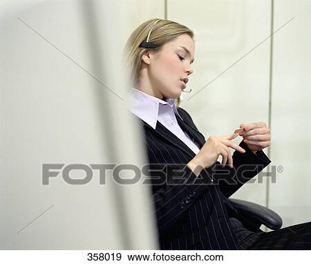 Receptionist sitting at desk and filing her nails View Large Photo Image Stock Photo - Receptionist sitting at desk and filing her nails. Fotosearch