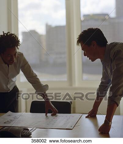Two businessmen looking at document on board room table View Large Photo Image Stock Image - Two businessmen looking at document on board room table. Fotosearch