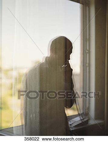 View through window of a businessman using a telephone View Large Photo Image Stock Image - View through window of a businessman using a telephone. Fotosearch