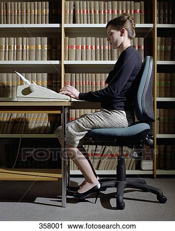 Woman sitting at desk using typewriter View Large Photo Image Stock Image - Woman sitting at desk using typewriter. Fotosearch