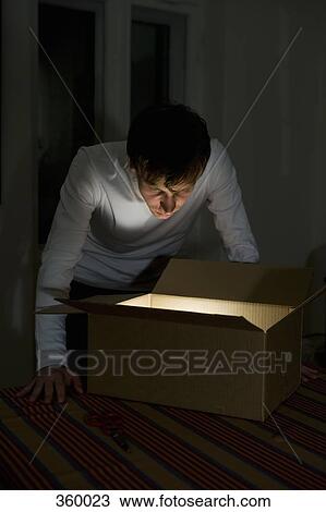 Young man staring into illuminated cardboard box View Large Photo Image Stock Image - Young man staring into illuminated cardboard box. Fotosearch
