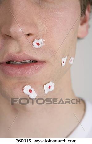 Stock Photography - Young man with tissue paper on shaving wounds. Fotosearch