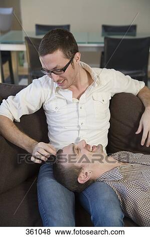 Gay couple relaxing on sofa together View Large Photo Image Stock Photo - Gay couple relaxing on sofa together. Fotosearch