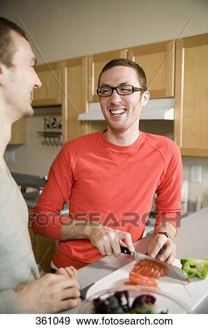 Two man preparing food together in kitchen and laughing View Large Photo Image Stock Photo - Two man preparing food together in kitchen and laughing. Fotosearch