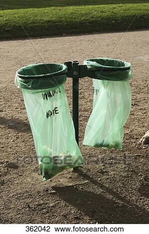 Stock Image - Plastic garbage bags in holders in a park. Fotosearch