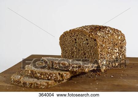 Picture - Multi-grain bread on wooden cutting board. Fotosearch