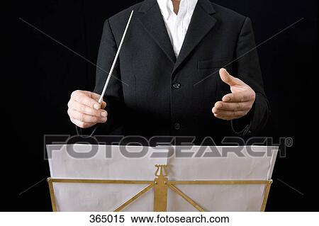 Stock Photography - Conductor standing behind stand with sheet music. Fotosearch