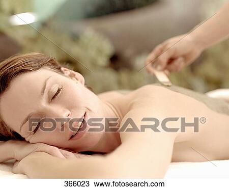 Stock Image - Woman having body mask applied at beauty spa. Fotosearch