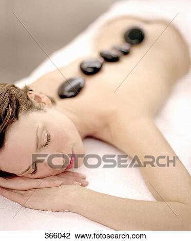 Woman lying down with therapeutic stones on her back View Large Photo Image Stock Image - Woman lying down with therapeutic stones on her back. Fotosearch
