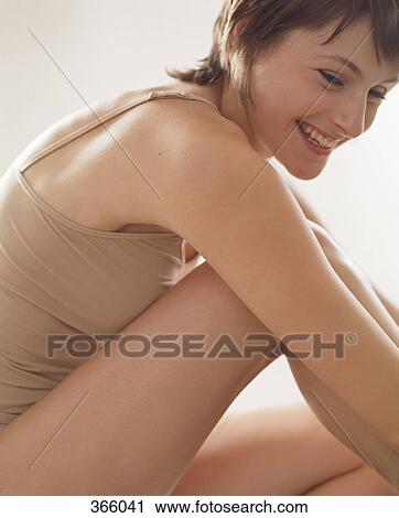 Stock Image - Woman sitting with bent leg. Fotosearch