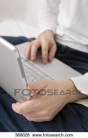 Midsection of person sitting with a laptop on their lap View Large Photo Image Stock Photograph - Midsection of person sitting with a laptop on their lap. Fotosearch