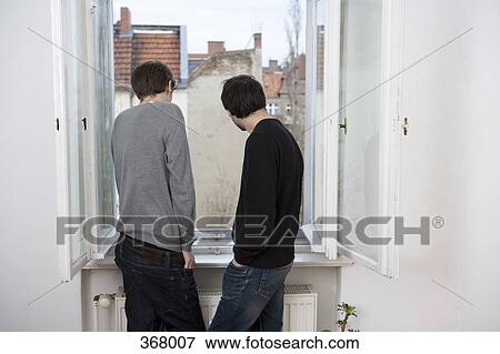 Two young men looking out of window View Large Photo Image Stock Photo - Two young men looking out of window. Fotosearch