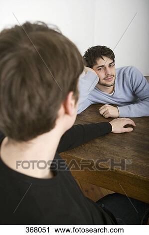 Young gay couple sitting at table together View Large Photo Image Stock Image - Young gay couple sitting at table together. Fotosearch