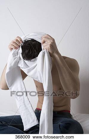 Stock Photo - Young man getting dressed. Fotosearch