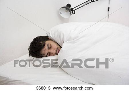 Stock Image - Young man sleeping in bed. Fotosearch