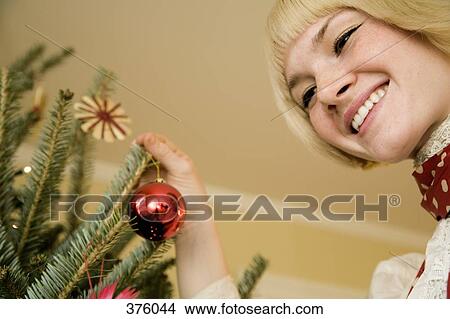 Young woman decorating a Christmas tree View Large Photo Image Picture - Young woman decorating a Christmas tree. Fotosearch