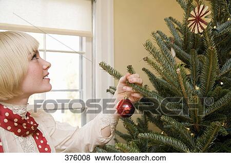 Stock Photo - Young woman decorating a Christmas tree. Fotosearch