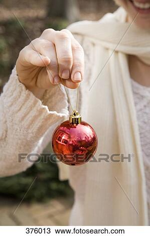 Stock Image - Young woman holding a Christmas bauble. Fotosearch