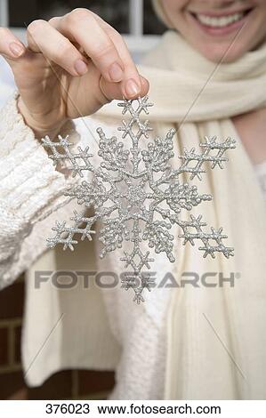 Young woman holding a decorative silver snowflake View Large Photo Image Stock Image - Young woman holding a decorative silver snowflake. Fotosearch