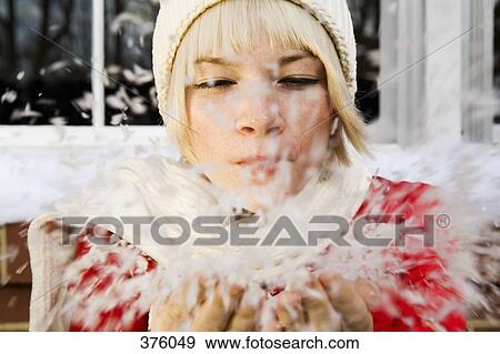 Young woman in winter clothing blowing a handful of snow View Large Photo Image Stock Photo - Young woman in winter clothing blowing a handful of snow. Fotosearch