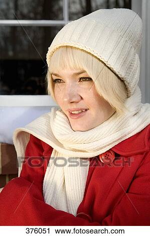 Stock Image - Young woman in winter clothing standing outside a house. Fotosearch