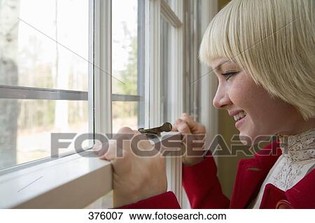 Young woman looking out a window View Large Photo Image Stock Photo - Young woman looking out a window. Fotosearch