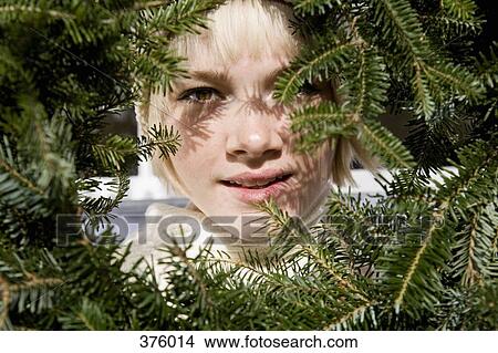 Young woman looking through a Christmas wreath View Large Photo Image Picture - Young woman looking through a Christmas wreath. Fotosearch