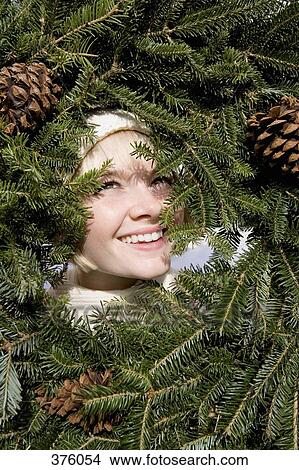 Young woman looking through a Christmas wreath View Large Photo Image Picture - Young woman looking through a Christmas wreath. Fotosearch