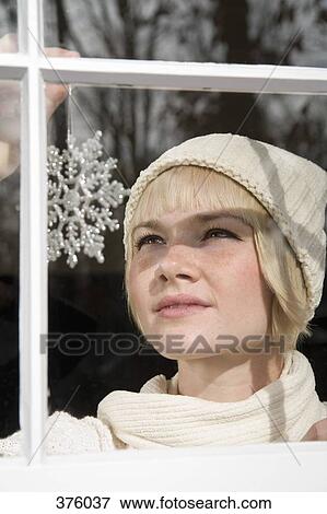 Young woman placing a silver decorative snowflake in a window View Large Photo Image Stock Photo - Young woman placing a silver decorative snowflake in a window. Fotosearch