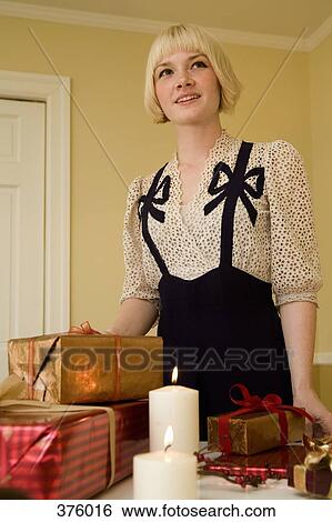 Stock Photograph - Young woman standing behind presents on a table. Fotosearch
