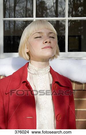 Young woman standing next to house with eyes closed View Large Photo Image Picture - Young woman standing next to house with eyes closed. Fotosearch