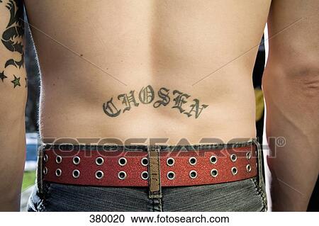 Stock Image - Close-up of a man with ‘chosen’ tattoo on his back. Fotosearch