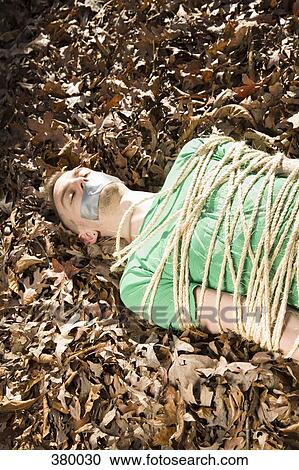 Man lying on the ground, bound in rope and with adhesive tape covering his mouth View Large Photo Image Stock Image - Man lying on the ground, bound in rope and with adhesive tape covering his mouth. Fotosearch