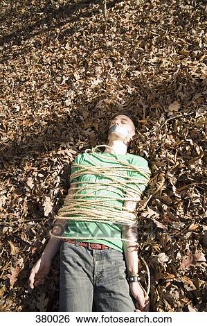 Man lying on the ground, bound in rope and with adhesive tape covering his mouth View Large Photo Image Stock Photograph - Man lying on the ground, bound in rope and with adhesive tape covering his mouth. Fotosearch