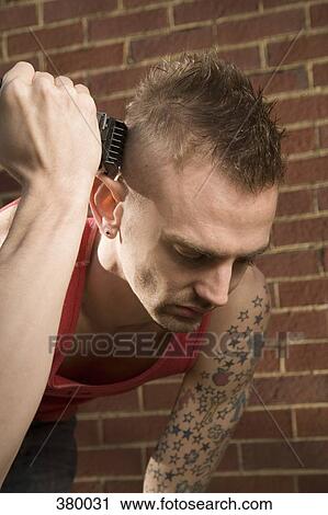 Stock Image - Man shaving his head with an electric razor. Fotosearch