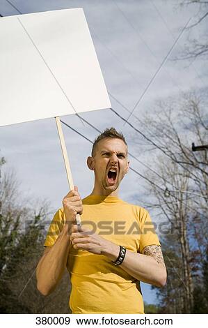 Man shouting and holding a blank placard View Large Photo Image Stock Photo - Man shouting and holding a blank placard. Fotosearch