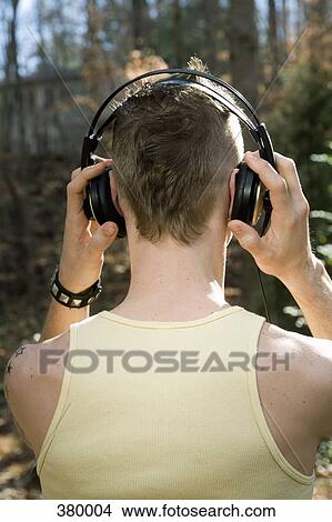 Man standing in the woods and wearing headphones View Large Photo Image Picture - Man standing in the woods and wearing headphones. Fotosearch