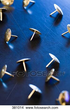 Picture - Group of gold thumb tacks on a desk. Fotosearch