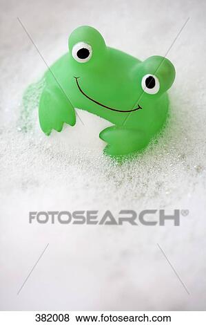 Stock Photo - Green toy floating in bubble bath. Fotosearch