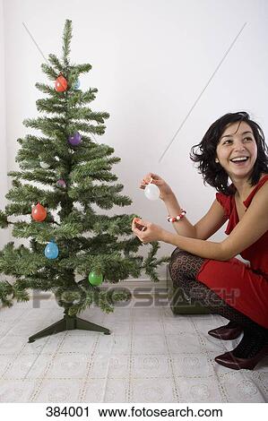 Woman crouching by Christmas tree View Large Photo Image Stock Image - Woman crouching by Christmas tree. Fotosearch