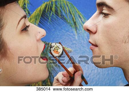 Man feeding sushi to his girlfriend View Large Photo Image Picture - Man feeding sushi to his girlfriend. Fotosearch