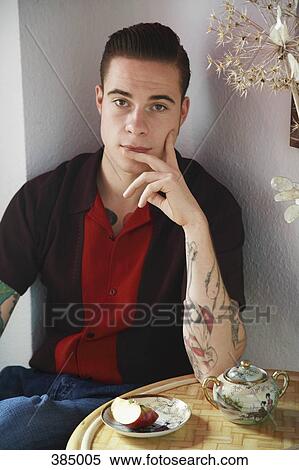 Stock Photography - Young rockabilly man sitting at table. Fotosearch