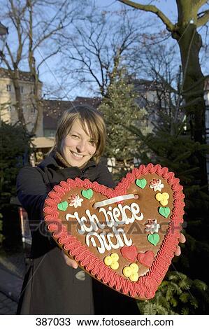 Woman holding a heart-shaped gingerbread cookie View Large Photo Image Stock Image - Woman holding a heart-shaped gingerbread cookie. Fotosearch