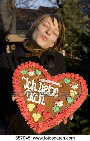 Woman holding a heart-shaped gingerbread cookie and puckering her lips View Large Photo Image Stock Photography - Woman holding a heart-shaped gingerbread cookie and puckering her lips. Fotosearch