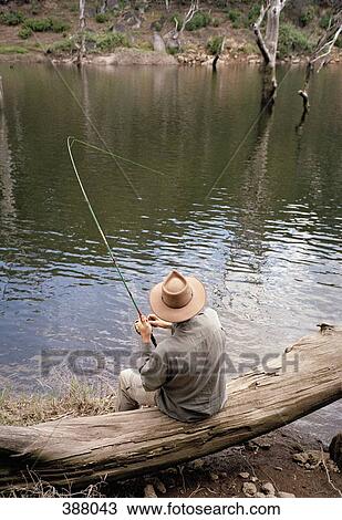 Man fishing from a log on a riverbank View Large Photo Image Stock Image - Man fishing from a log on a riverbank. Fotosearch