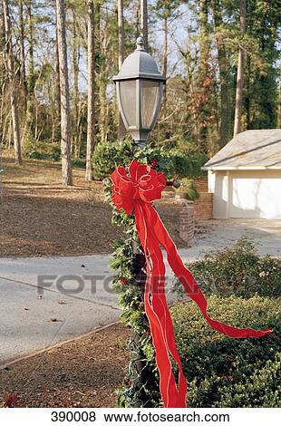 Lamppost decorated with Christmas lights, ribbon and holly View Large Photo Image Stock Photo - Lamppost decorated with Christmas lights, ribbon and holly. Fotosearch